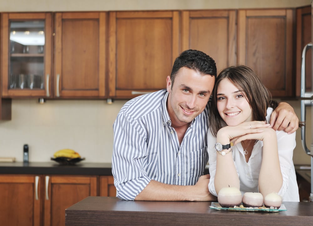 happy young couple have fun in modern wooden  kitchen indoor while preparing fresh food